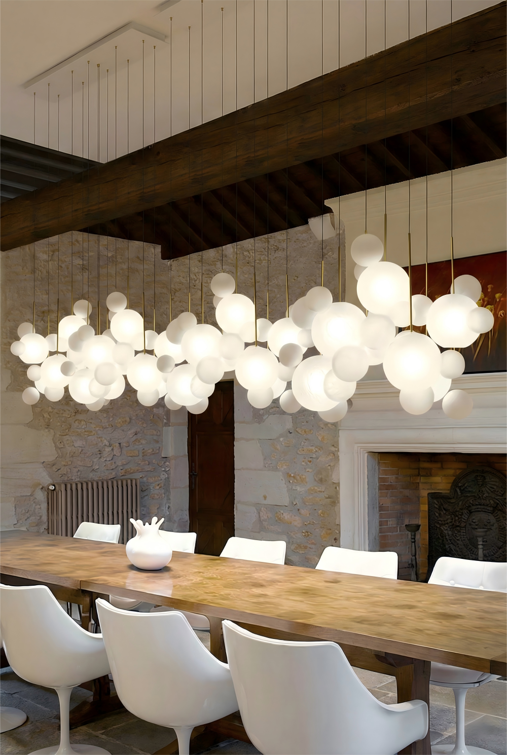 Modern chandelier hanging above a dining table with white chairs in a stylish room.