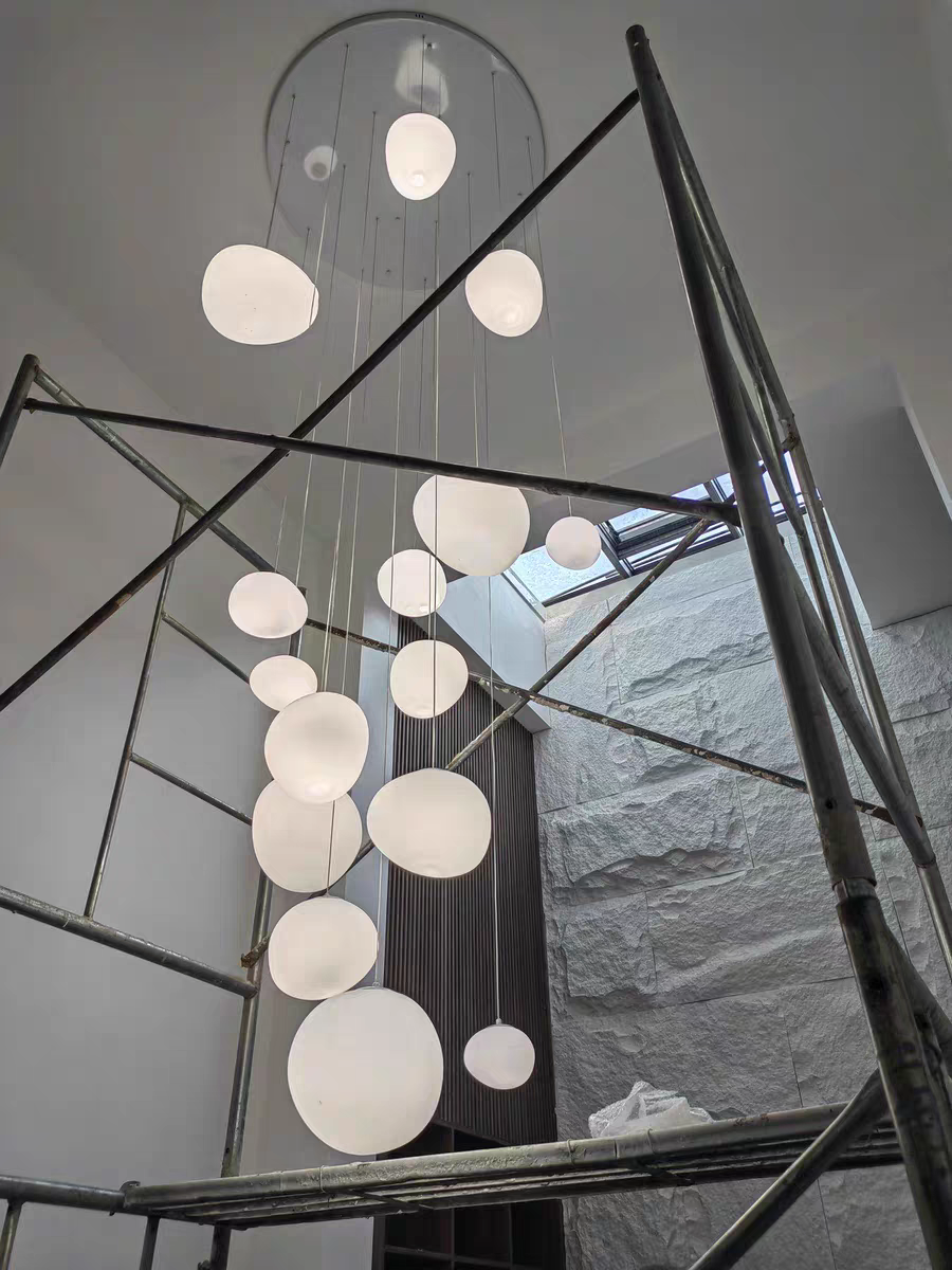 View from below the illuminated Luminous Pebble pendant, showcasing its even light diffusion.