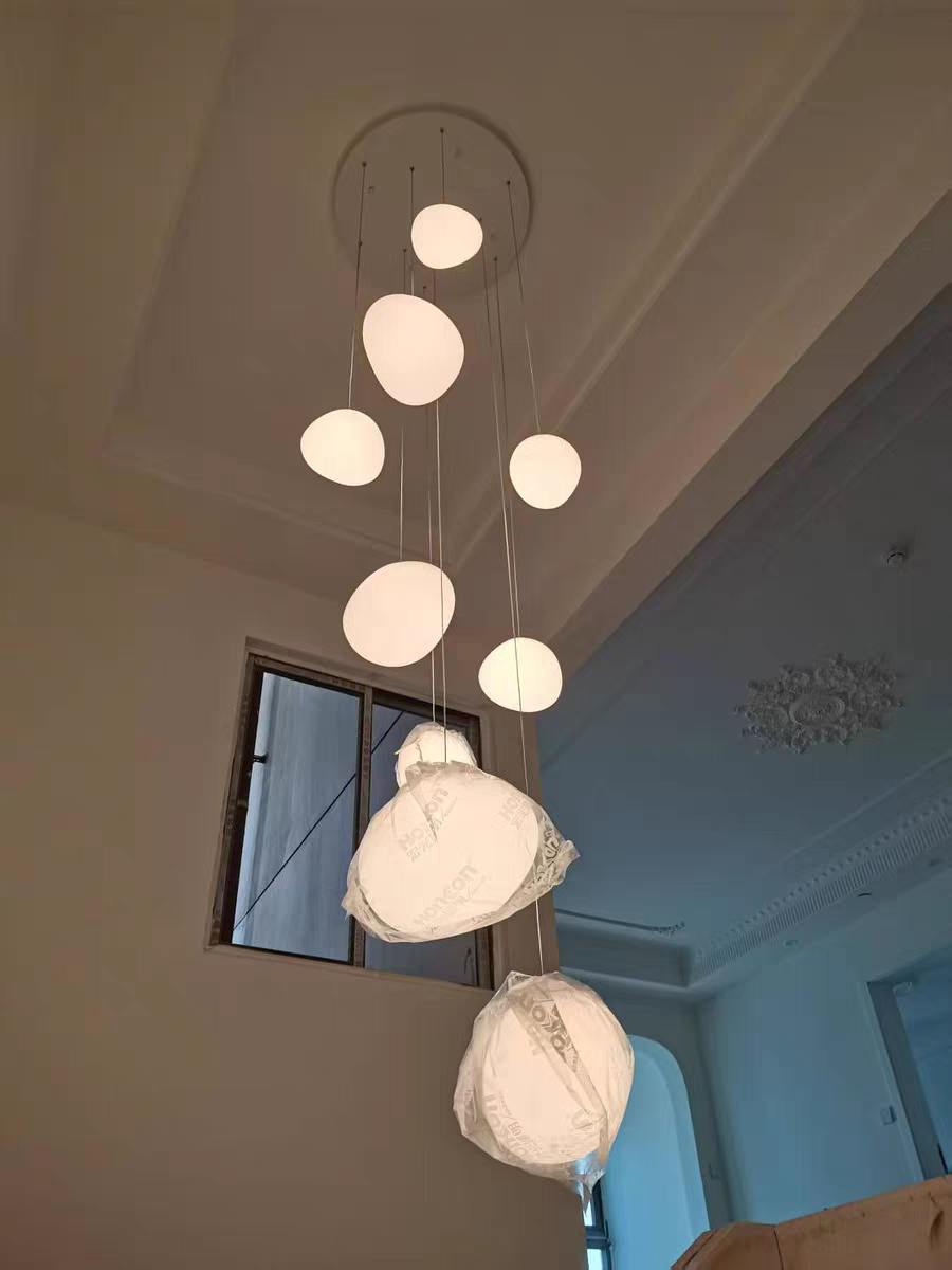 Illuminated Luminous Pebble pendant emitting a soft, diffused warm white glow, highlighting its organic shape.