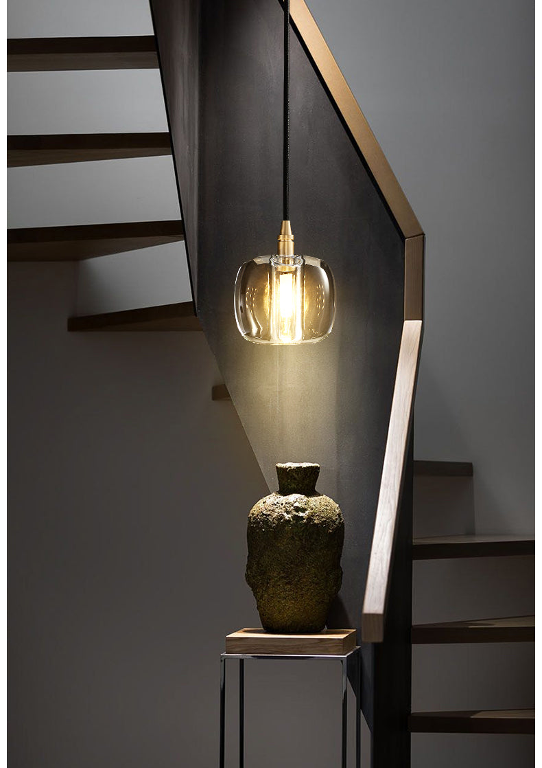 Illuminated Luminous Column crystal and brass pendant, emitting a warm, radiant glow.