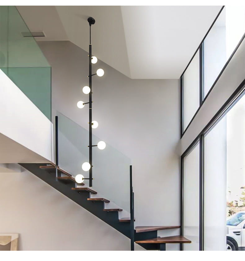 A view from directly beneath the linear chandelier, showcasing the rhythmic symmetry of its glowing white glass orbs.