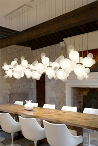 Thumbnail for Modern chandelier hanging above a dining table with white chairs in a stylish room.
