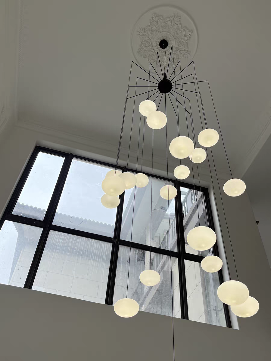Illuminated chandelier, diffusing a warm, even glow through its white glass pendants.