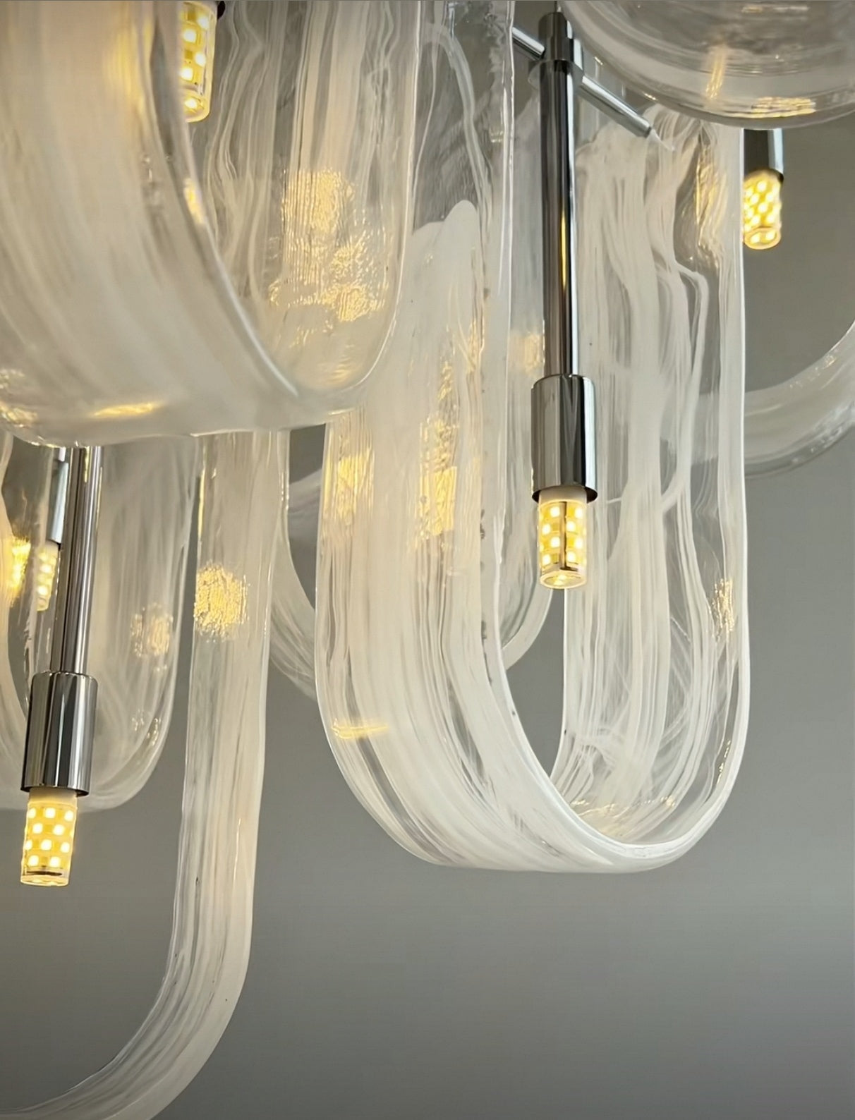 Close-up of hand-blown frosted glass pendants on Nebula Wave Chandelier, diffusing soft light