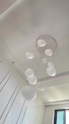 Lifestyle image of the Luminous Pebble pendants in a cozy reading nook, providing focused illumination.