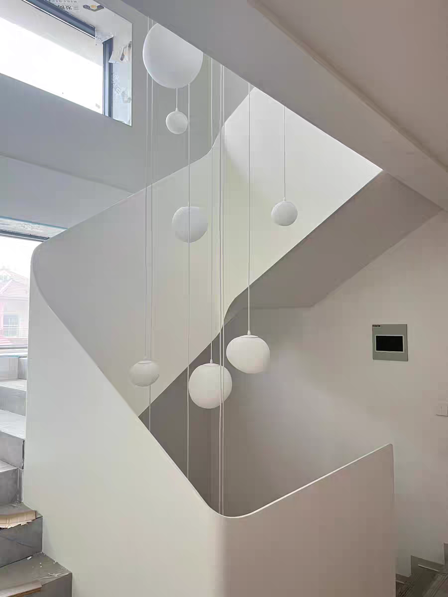 Unlit Luminous Pebble pendants arranged on a surface, displaying their sculptural, pebble-like qualities.