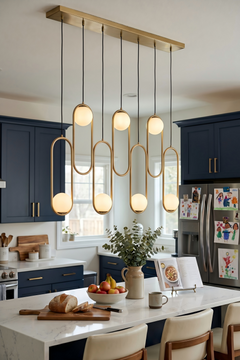 Modern minimalist chandelier above a marble kitchen island with deep navy blue shaker cabinets and stainless appliances