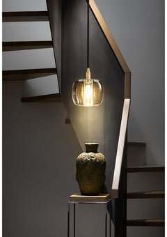 Illuminated Luminous Column crystal and brass pendant, emitting a warm, radiant glow.