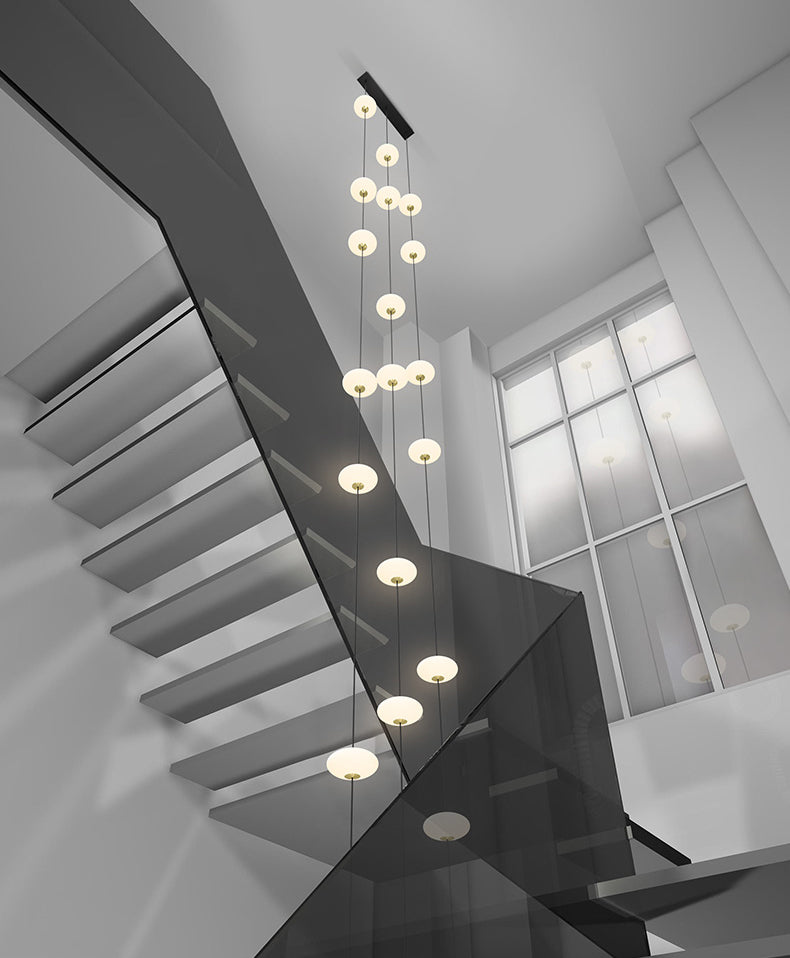 An oval pendant light with a frosted white and gold finish, featuring a series of LED lights hung in a staircase with a black canopy.