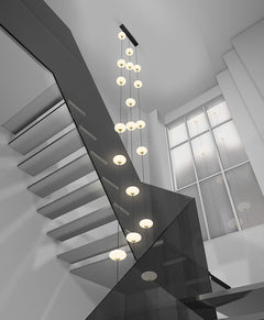 An oval pendant light with a frosted white and gold finish, featuring a series of LED lights hung in a staircase with a black canopy.